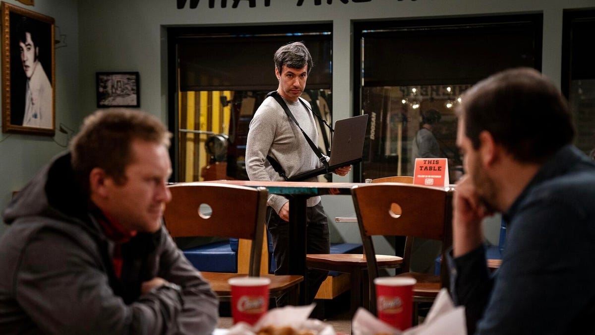 Nathan Fielder on the set of The Rehearsal with two men sitting in the foreground.
