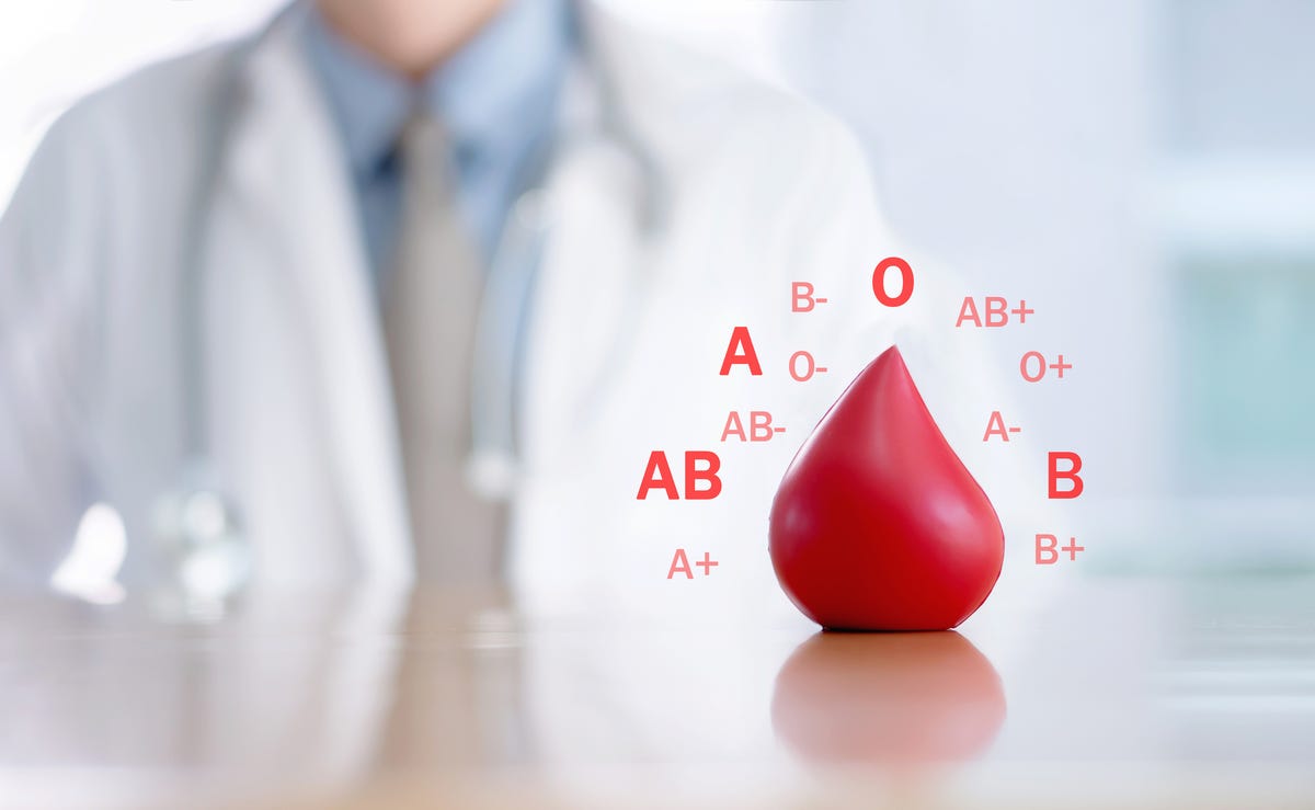 Photo illustration of a doctor sitting in front of a large drop of blood with blood types surrounding it