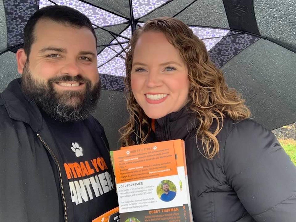 Joel Folkemer and his wife, both smiling, with campaign material