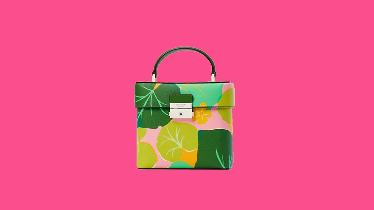 Close up of a boxy floral handbag covered in green leaves and a pink canvas background