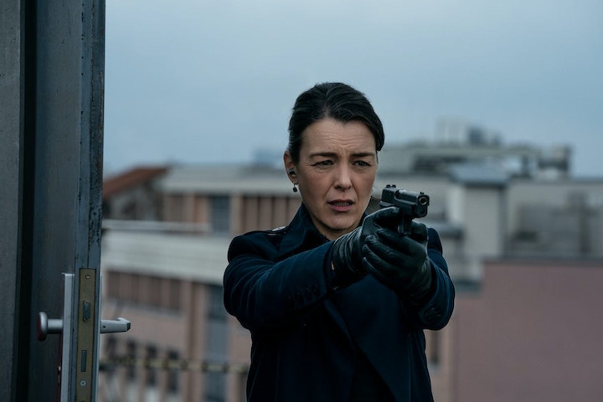Olivia Williams pointing a gun at a rooftop