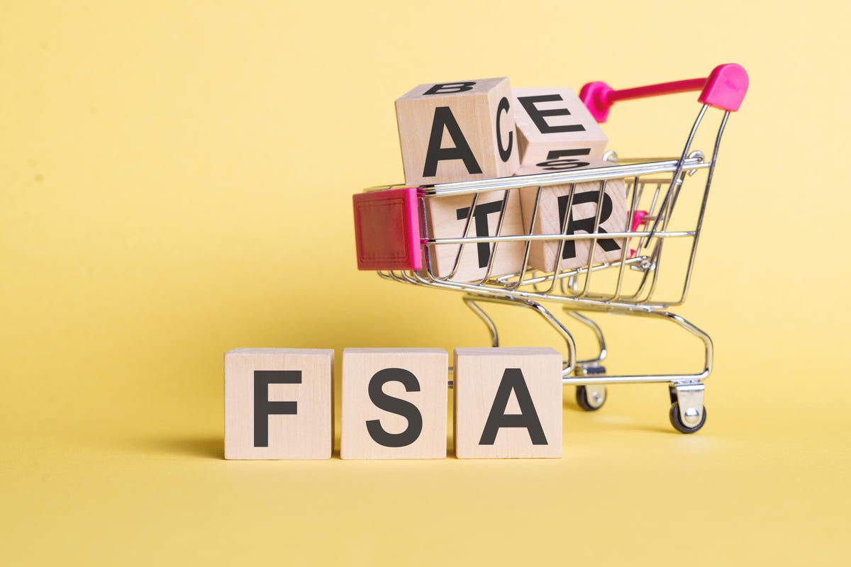 the letters F, S and A appear on wooden blocks in front of a shopping cart loaded with blocks featuring other letters