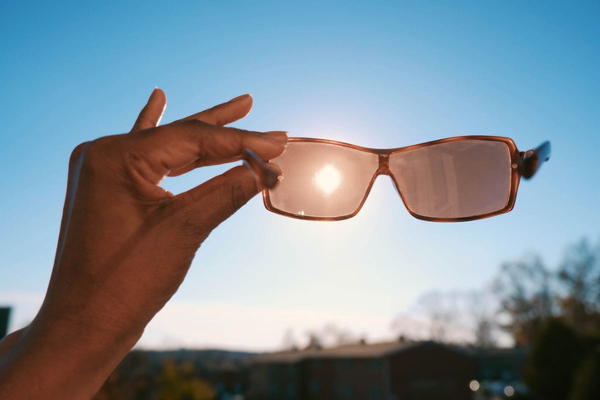 Person holding sunglasses up to the sun