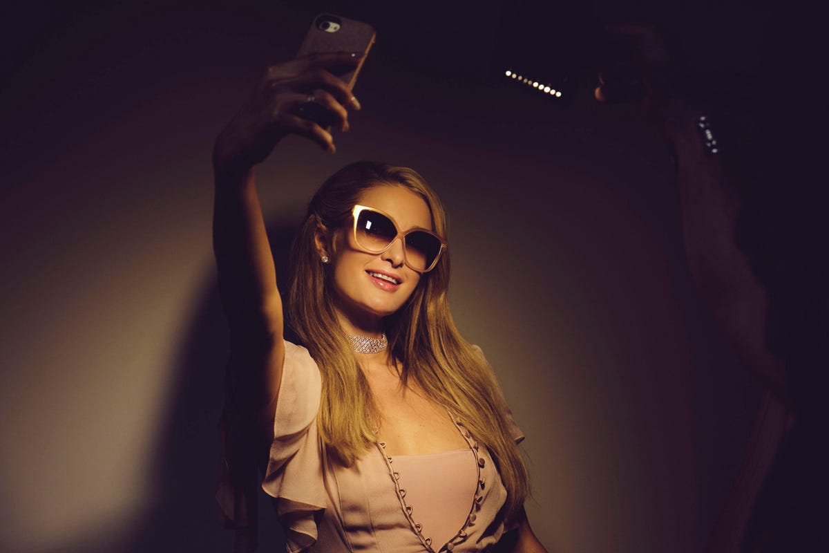 Paris Hilton poses for a selfie underneath a light