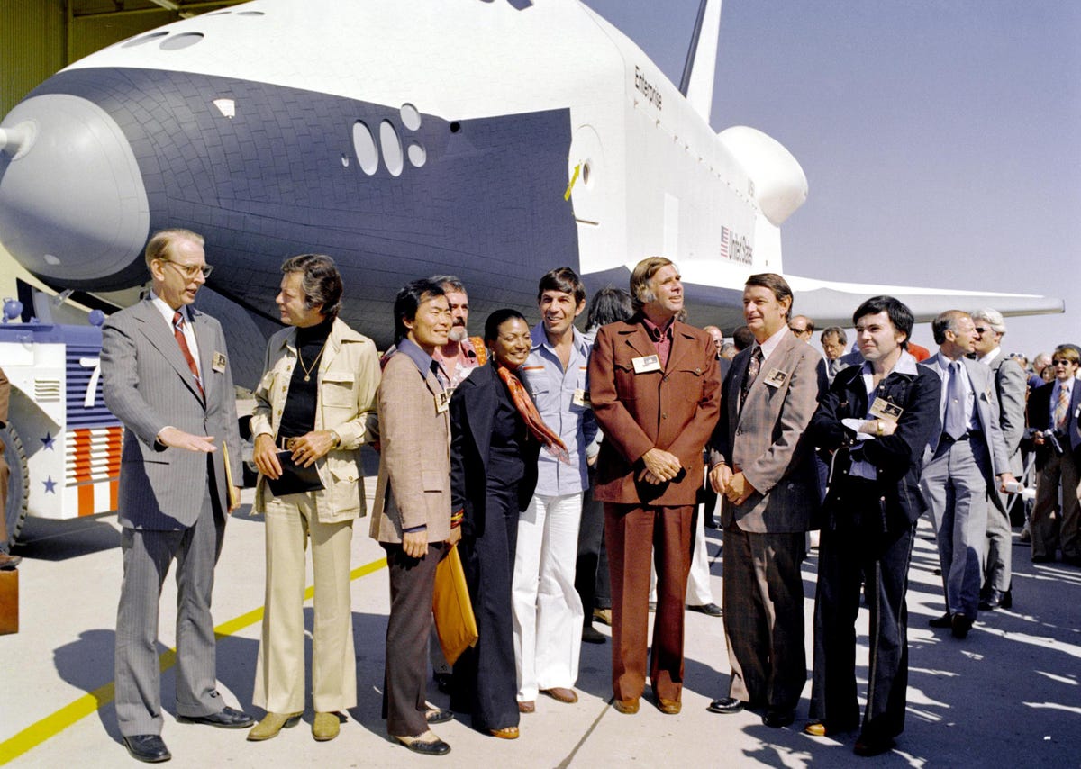 Members of the original Star Trek cast stand in front of the space shuttle Enterprise in 1976. Left to right: James D. Fletcher, NASA administrator; DeForest Kelley (Dr. McCoy); George Takei (Mr. Sulu); Nichelle Nichols (Lt. Uhura); Leonard Nimoy (Mr. Spock); Gene Roddenberry (Star Trek's creator); an unidentified man; and Walter Koenig (Ensign Pavel Chekov). The bearded fellow behind Takei and Nichols appears to be James Doohan (Mr. Scott).