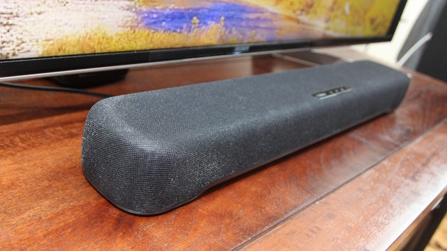 A side view of a gray Yamaha soundbar on a wooden TV stand.