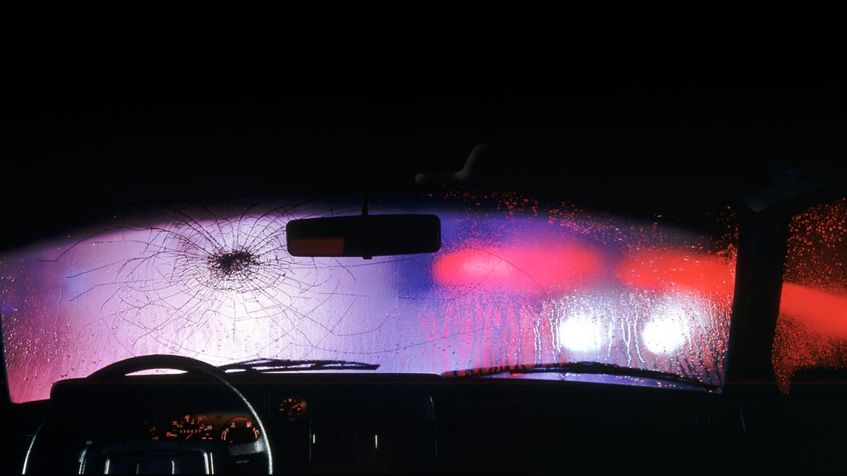 Cracked windshield with emergency vehicle lights showing through