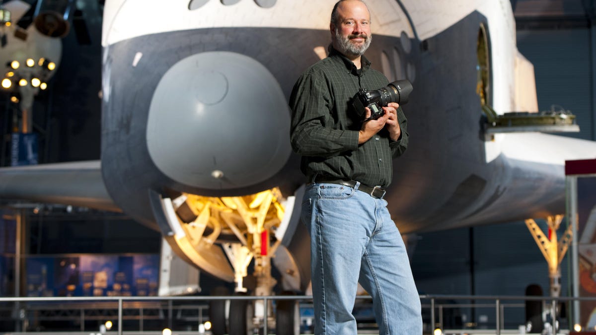 NASA photographer Bill Ingalls stands in front of a space shuttle.