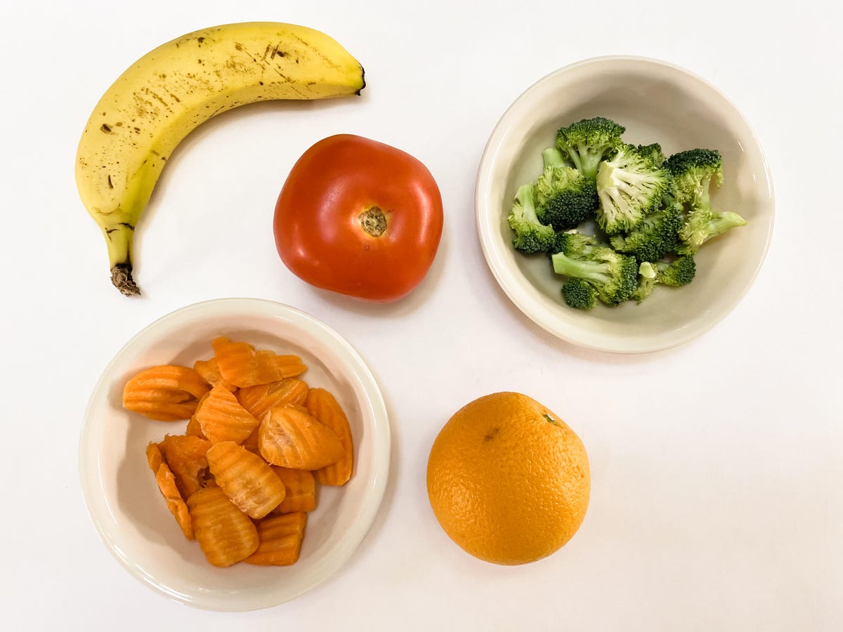 Five servings of produce: one medium banana, one tomato, one orange, a half cup of broccoli and a half cup of carrots.