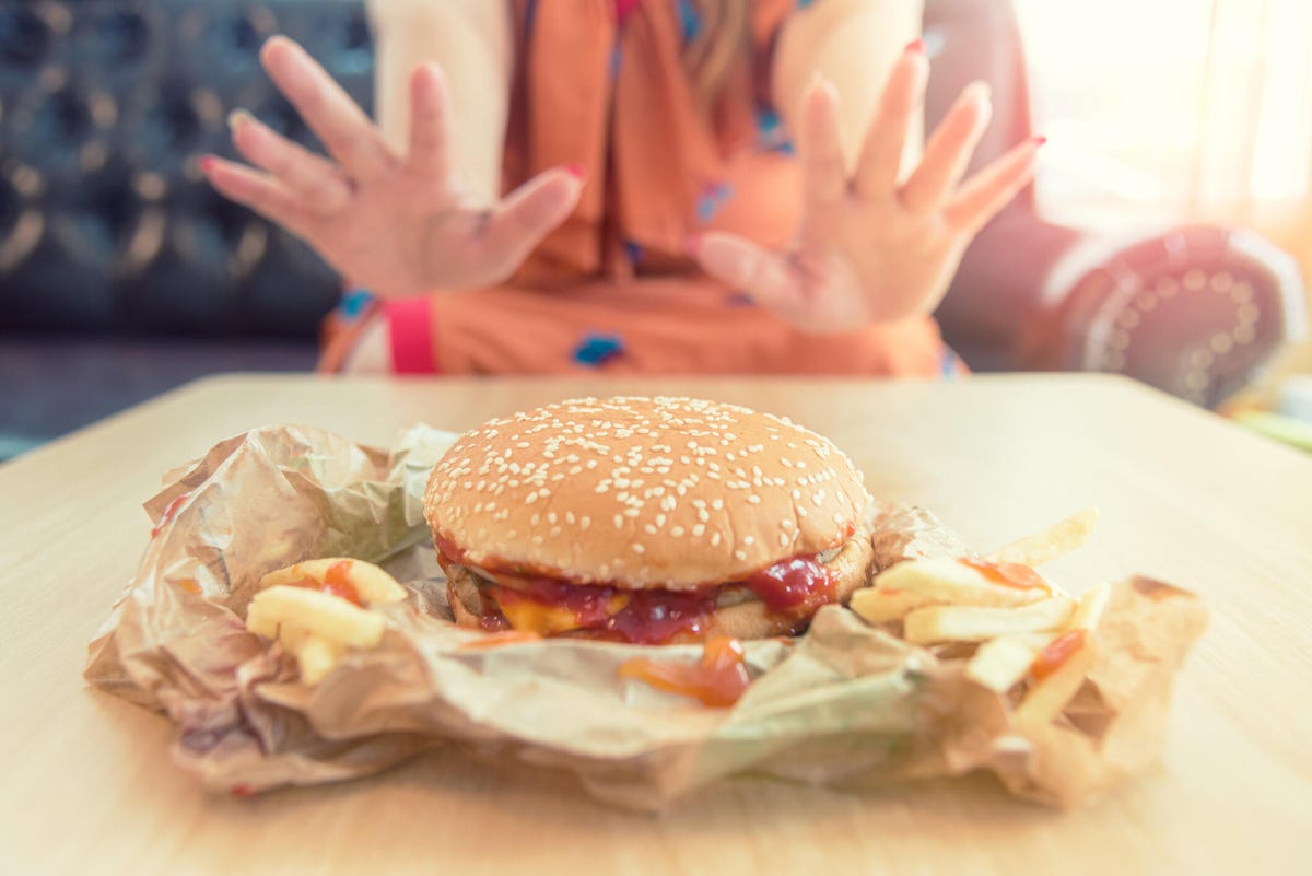 close up of hands woman refusing a cheeseburger on a diet