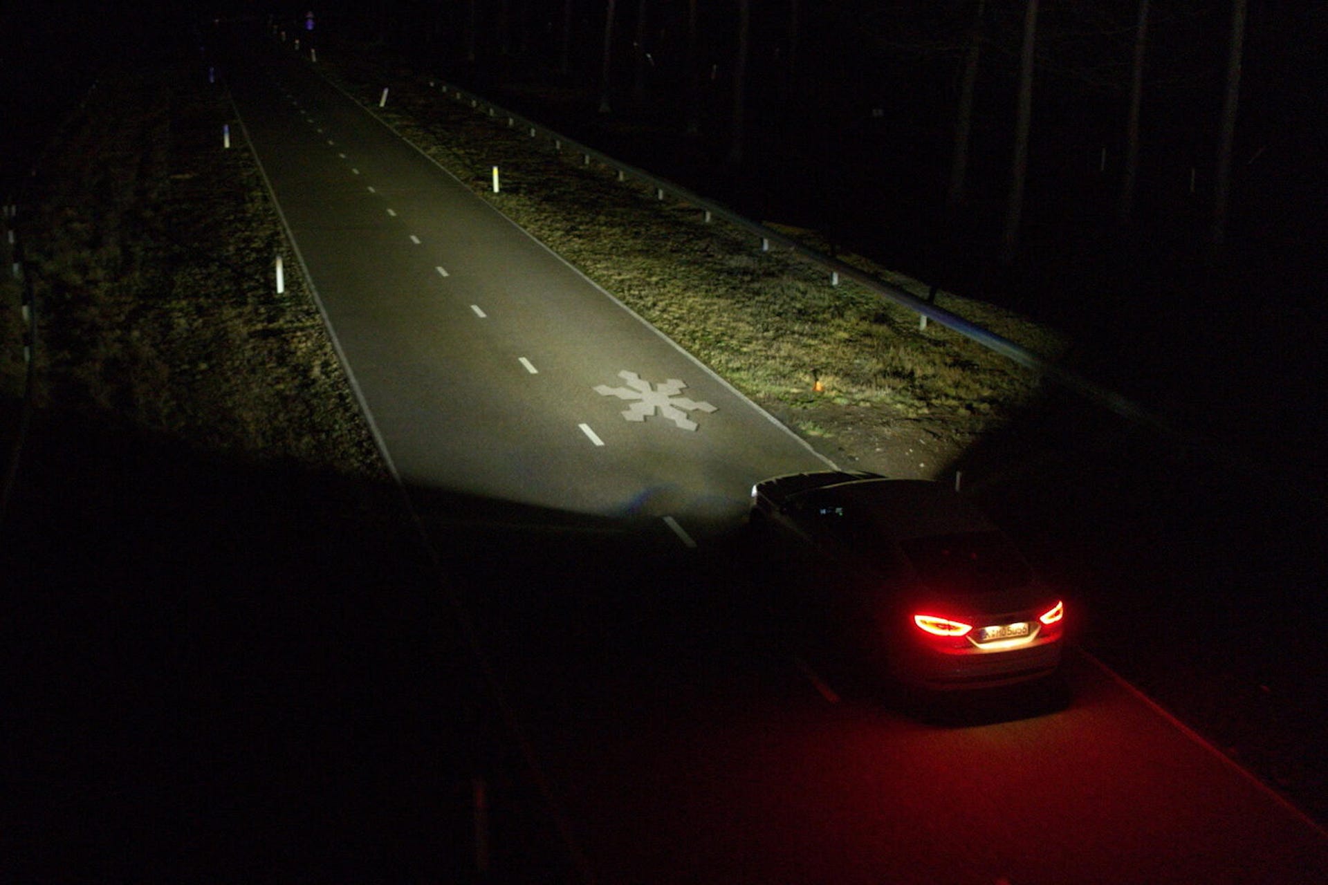 a car driving at night projects a snowflake onto the road from its headlights