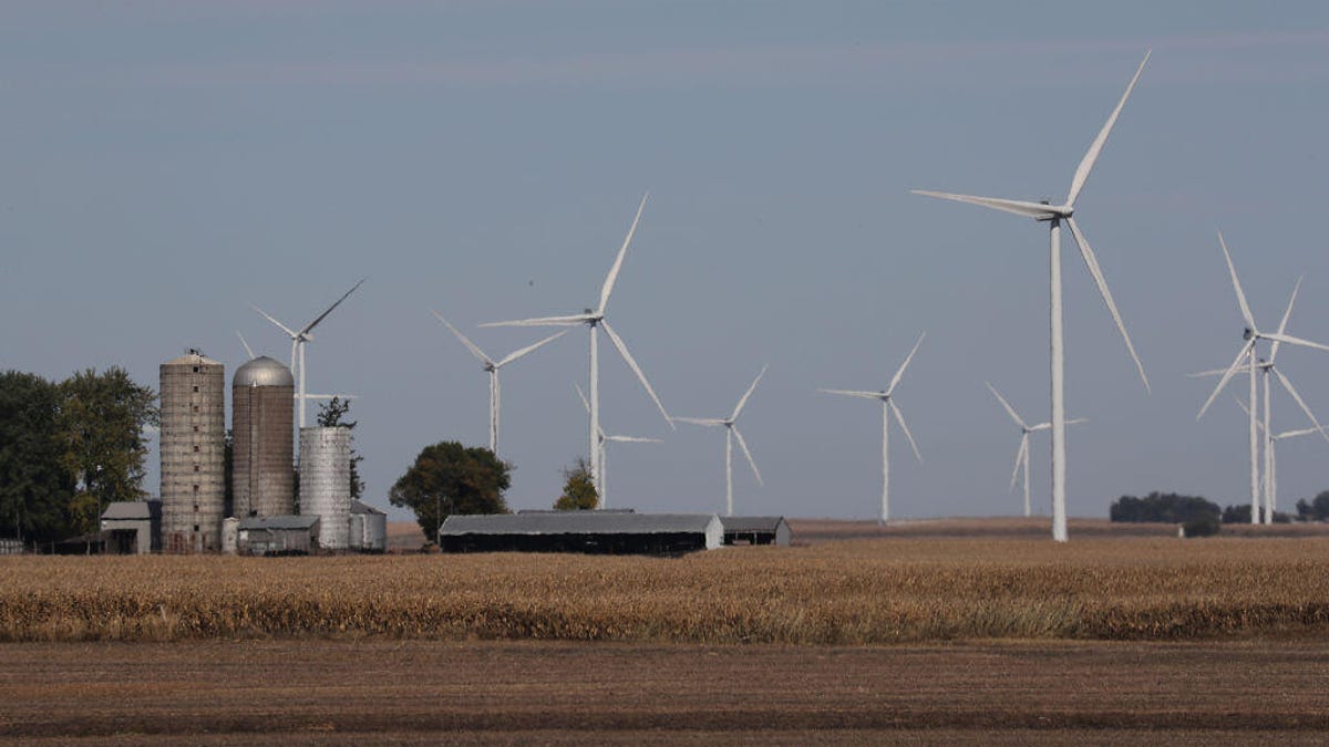 Wind turbines near a farm in Iowa, with fields and silos shown.