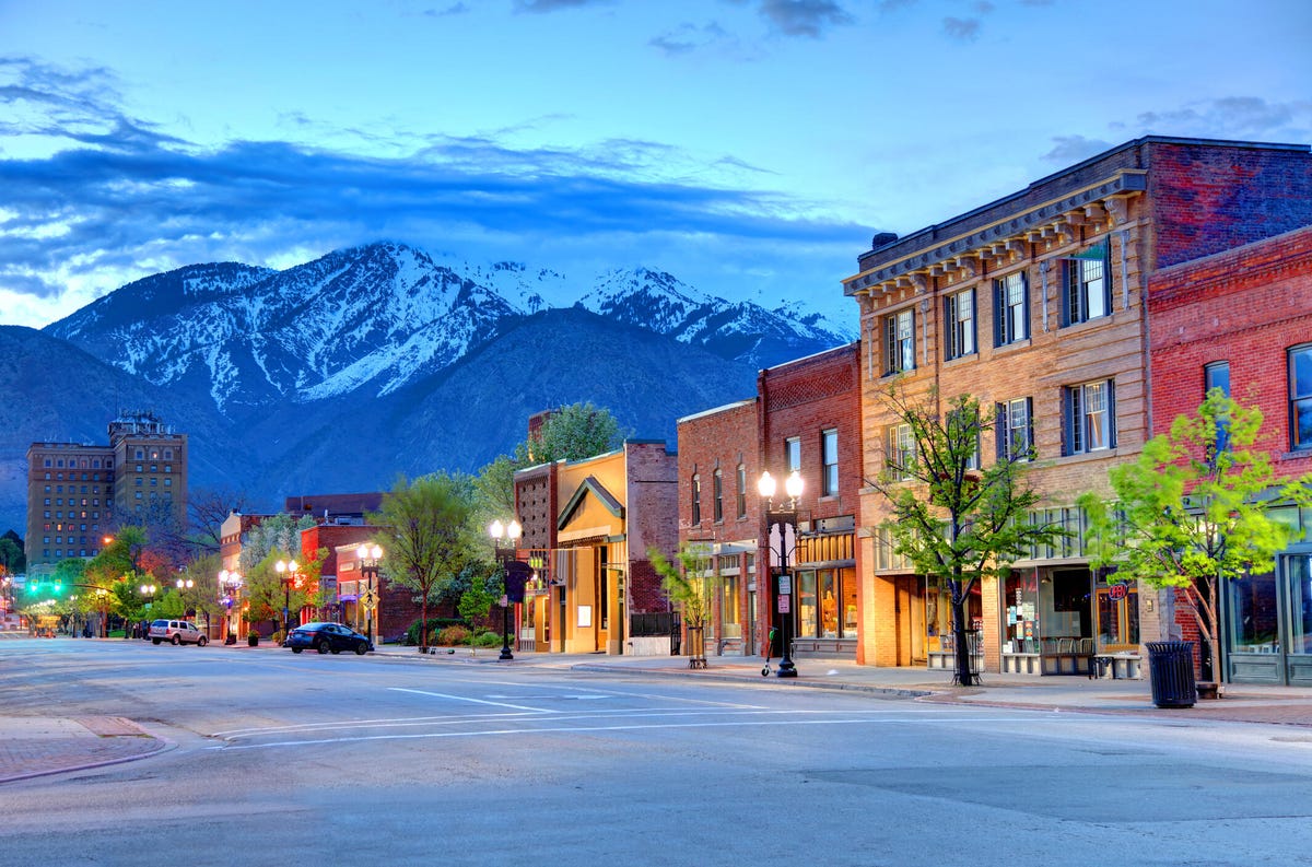 Historic 25th street in downtown Ogden, Utah, with scenic snowcapped mountains in the background.
