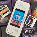 The white Evercade EXP game handheld on its side, with two game cartridges next to it