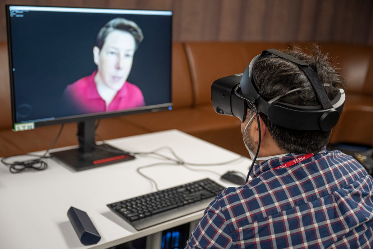 Man with a VR headset, chatting with a realistic avatar on a screen