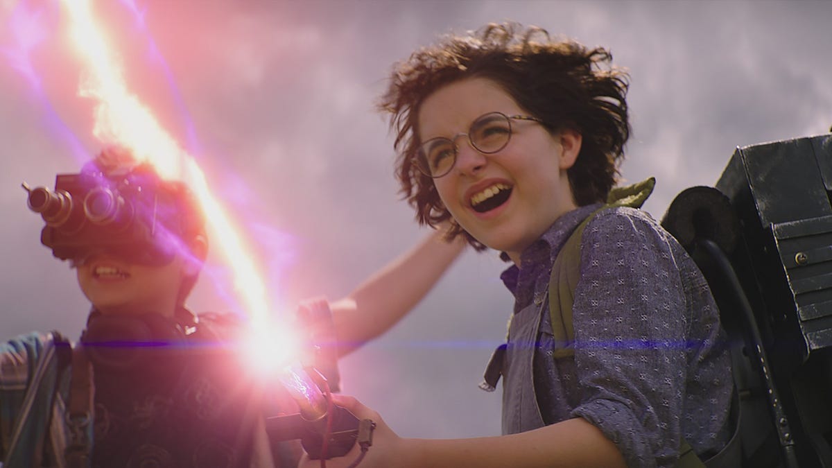 A teenage girl enjoys firing a Ghostbusters proton pack blaster