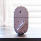 The August Smart Lock sitting upright on a table.