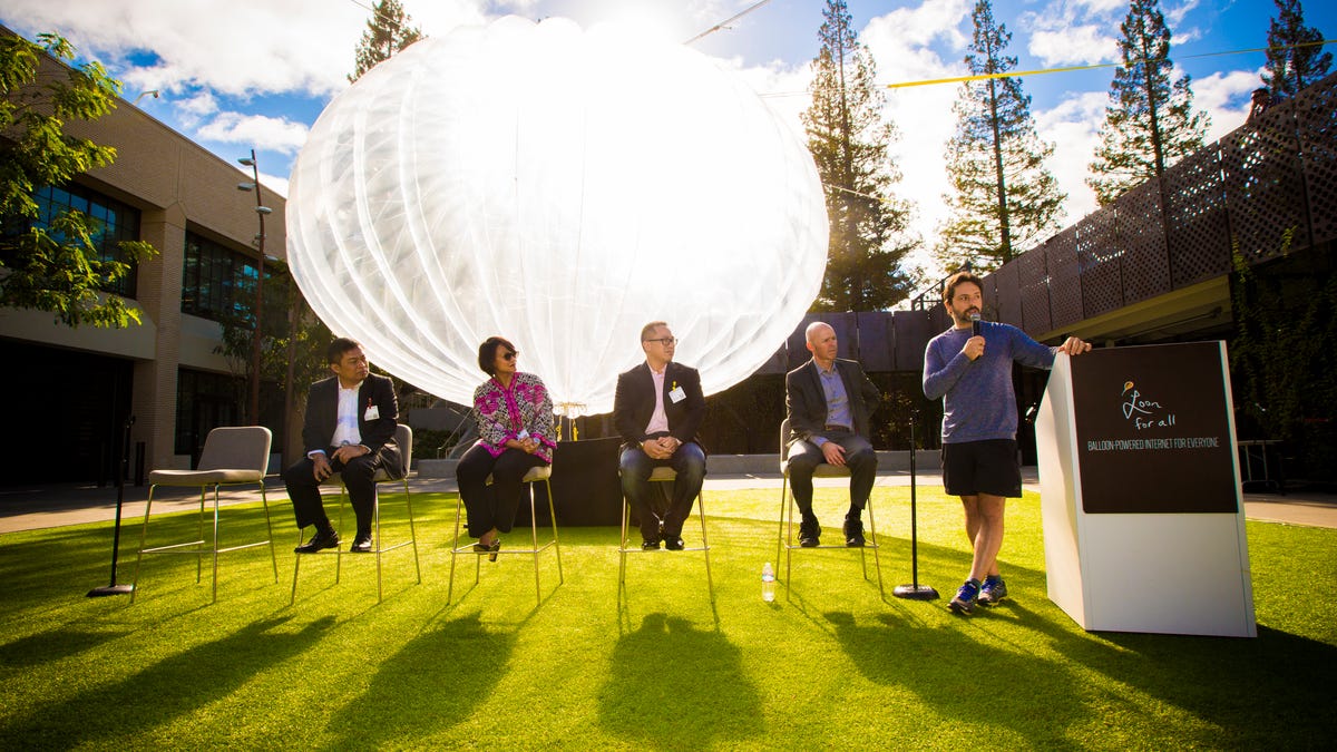 Google co-founder Sergey Brin works the mic as a Loon balloon and other guests look on.