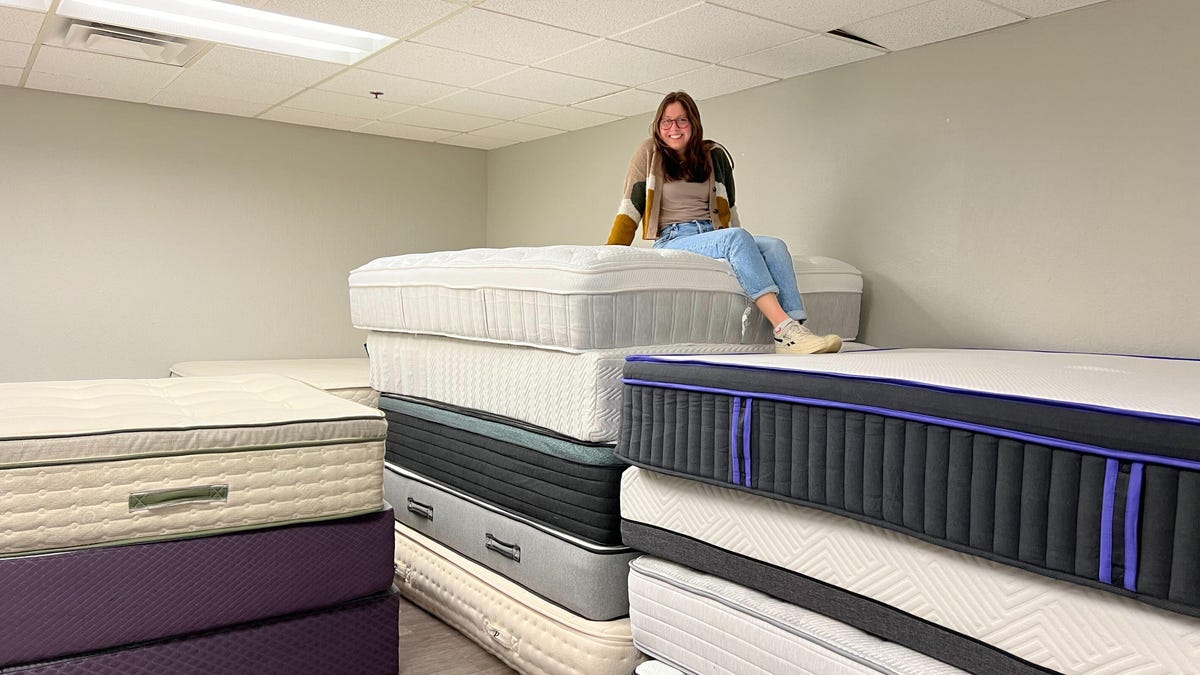 Caroline on top of a stacks of mattresses in the mattress warehouse.