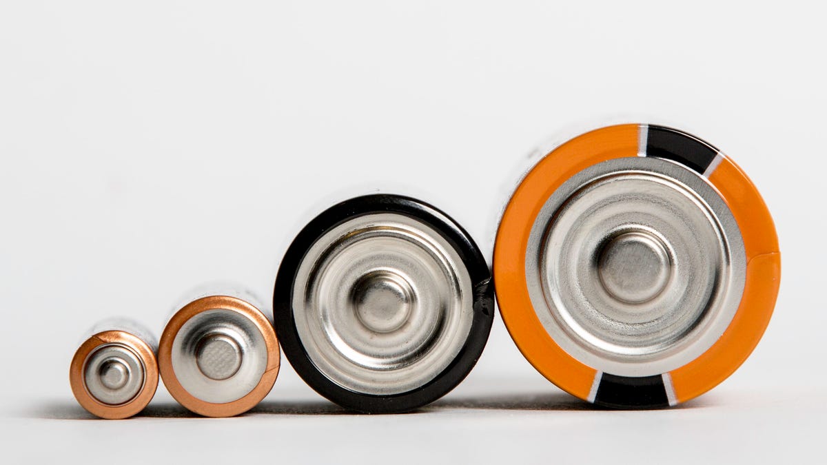 Four batteries are lined up from smallest to largest, with only the tops visible.