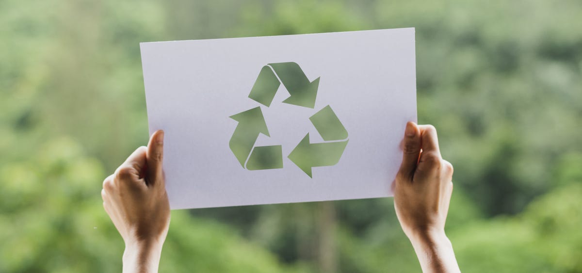 Hands holding a piece of paper with the recycling symbol on it