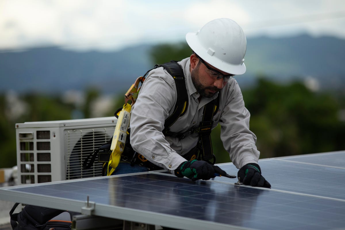 A worker installs solar panels in Puerto Rico