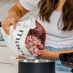 women pouring raw dog food into bowl