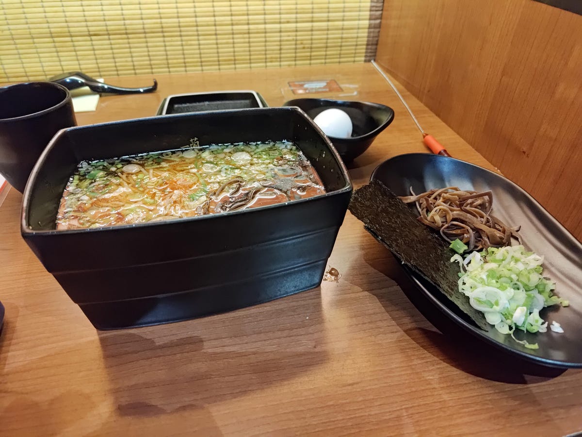 A black container of ramen and a smaller container of toppings