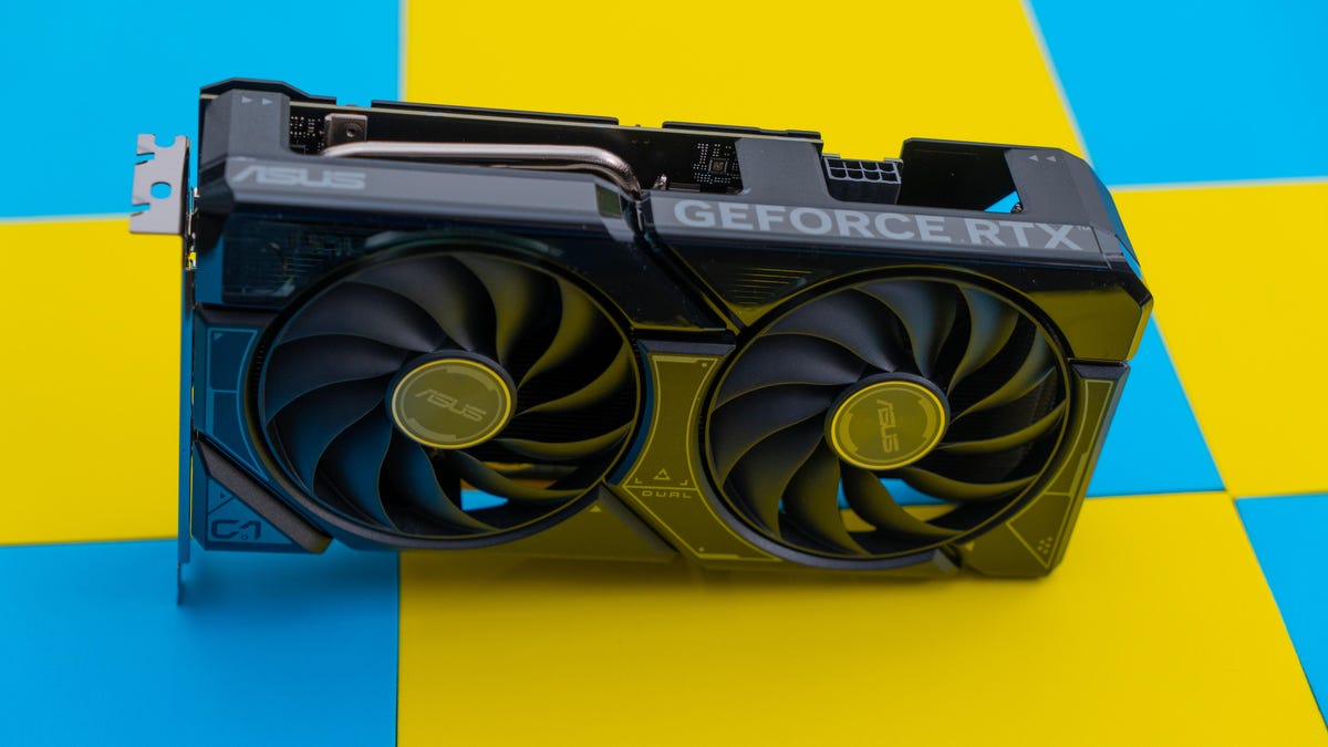 Asus Dual RTX 4060 standing on a blue and yellow checkerboard surface, fan side forward and tilted by the bottom of the end bracket