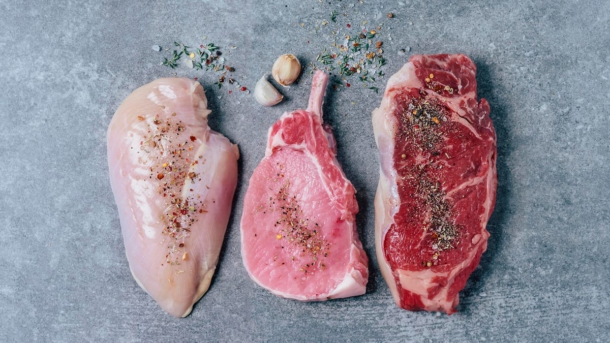 cuts of chicken, pork, and beef on a gray countertop