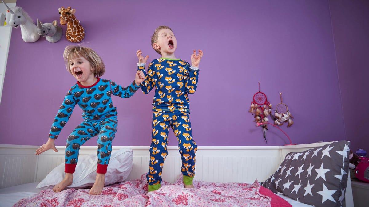 Young brother and sister wearing pajamas and jumping on the bed