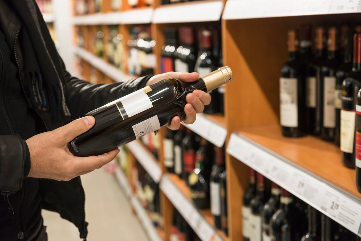 person holding bottle of wine in store