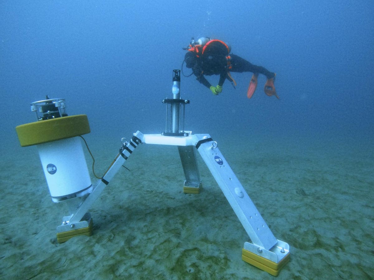 A research diver inspects a hydrophone lander deployed on the seafloor