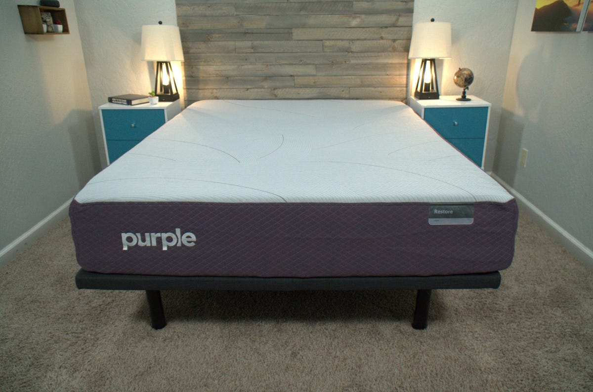 The Purple Restore mattress with a wooden bed frame against the back wall.