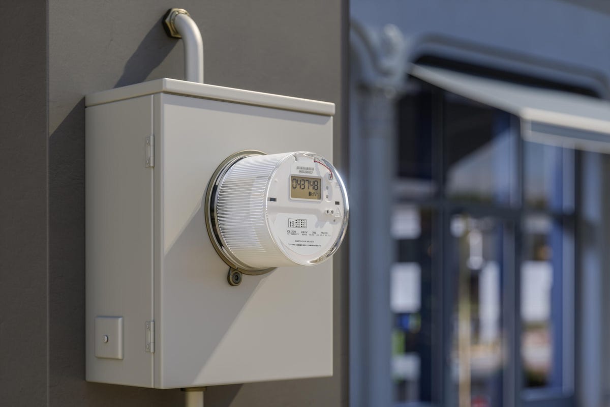 A close up view of an electric meter with a store front in the background.