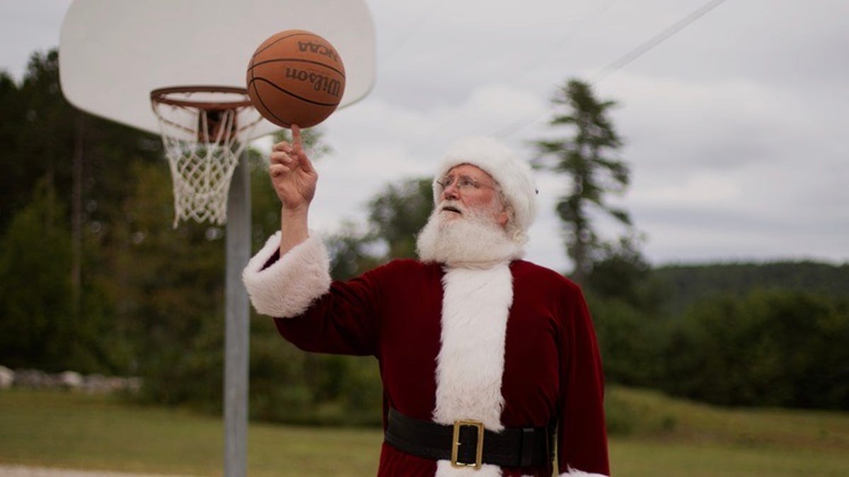 A santa spins a basketball on their finger.