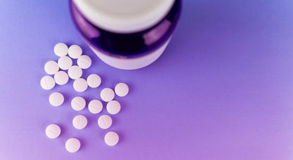 Bottle with melatonin pills or supplements, purple background