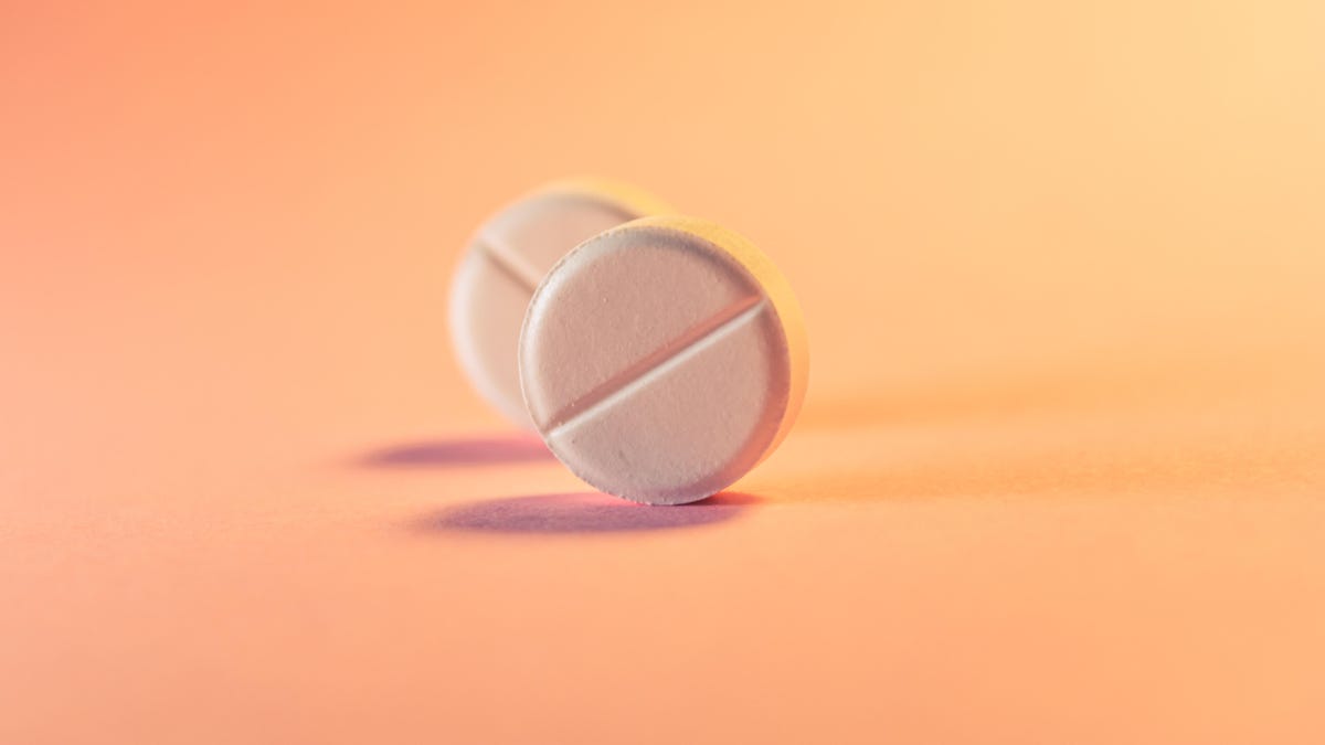 Two pills, standing on edge, against a light orange background.