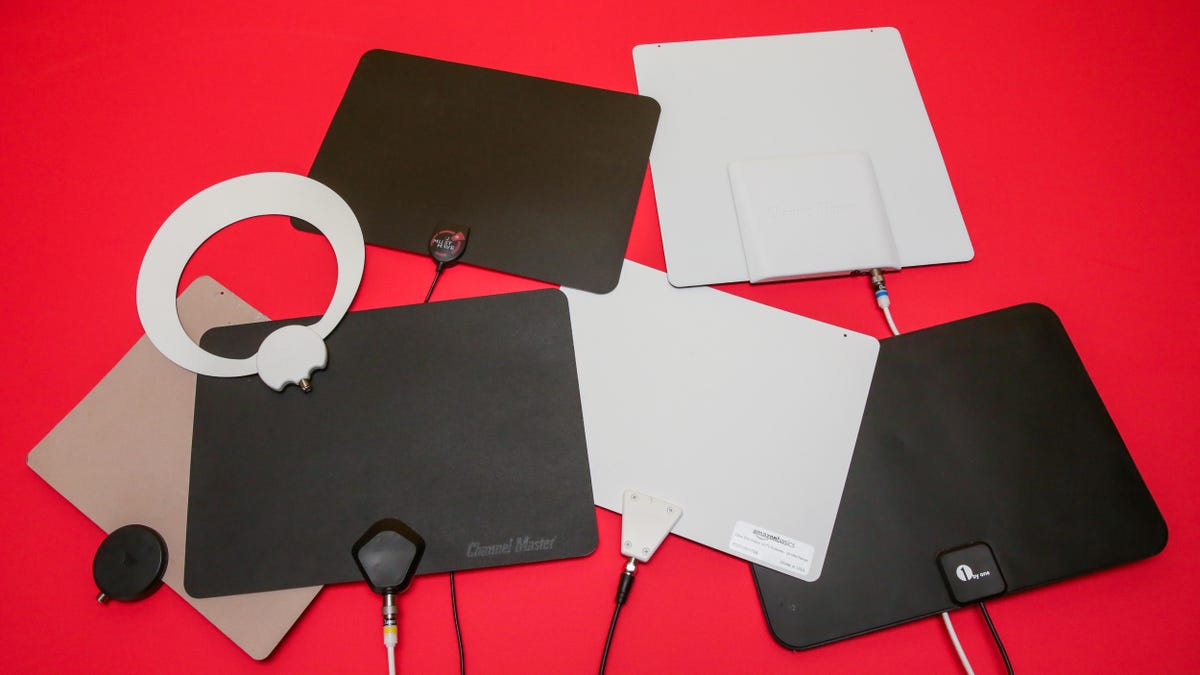 Several different black and white flat TV antennas laid out against a red background.
