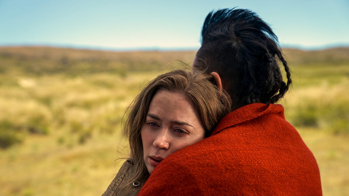 Emily Blunt and Chaske Spencer as Cornelia and Eli hugging in the Wild West