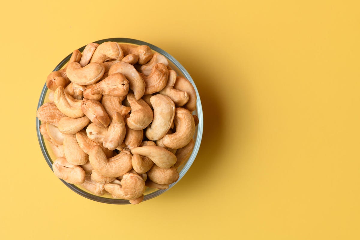 A bowl of cashews on a yellow background