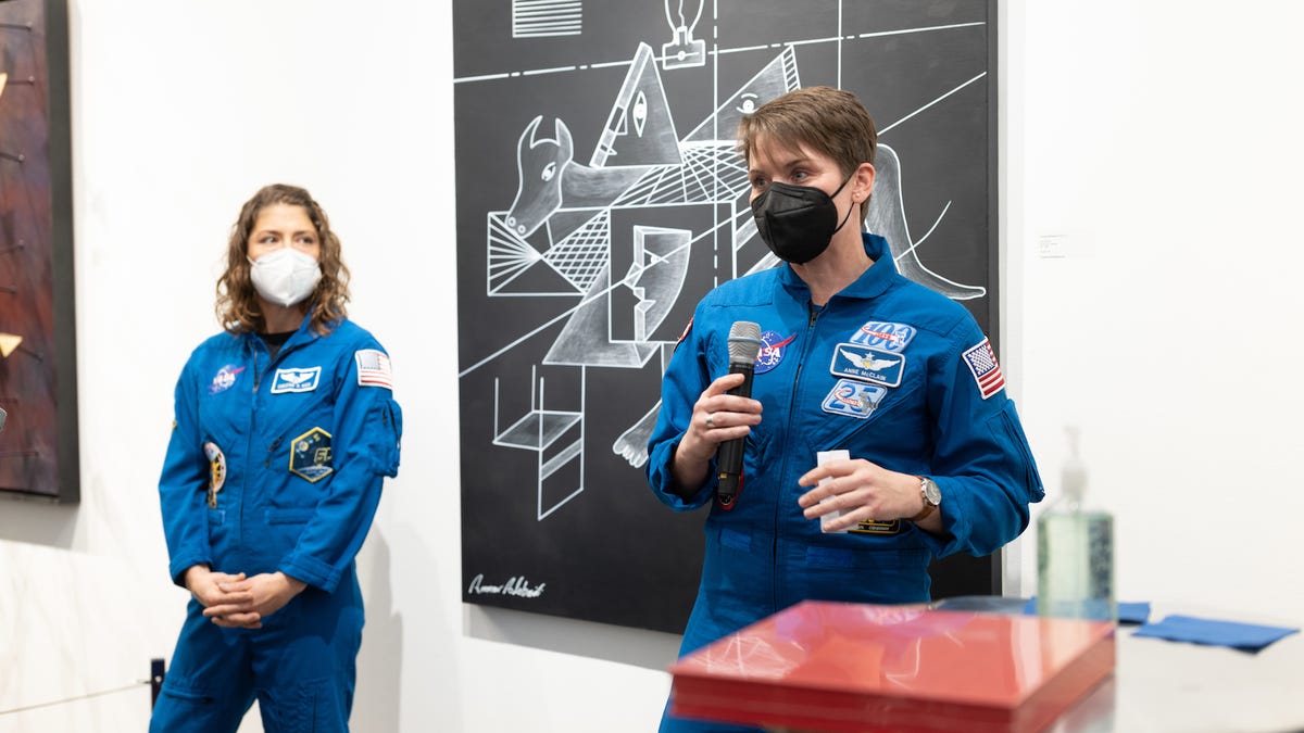 Astronauts Christina Koch and Anne McClain in blue jumpsuits with badges