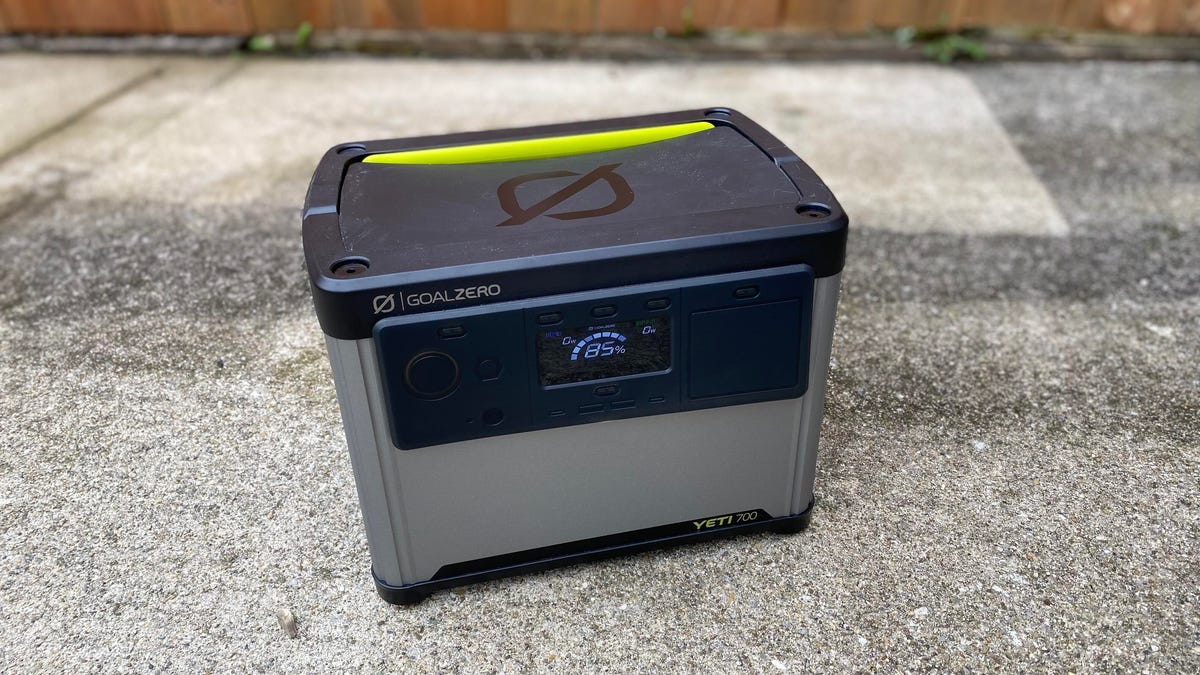 A gray and black portable power station sitting on a concrete patio.