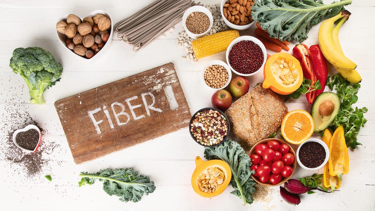 High fiber foods like nuts, chia seeds, quinoa, avocado, bread and nuts over a white background.