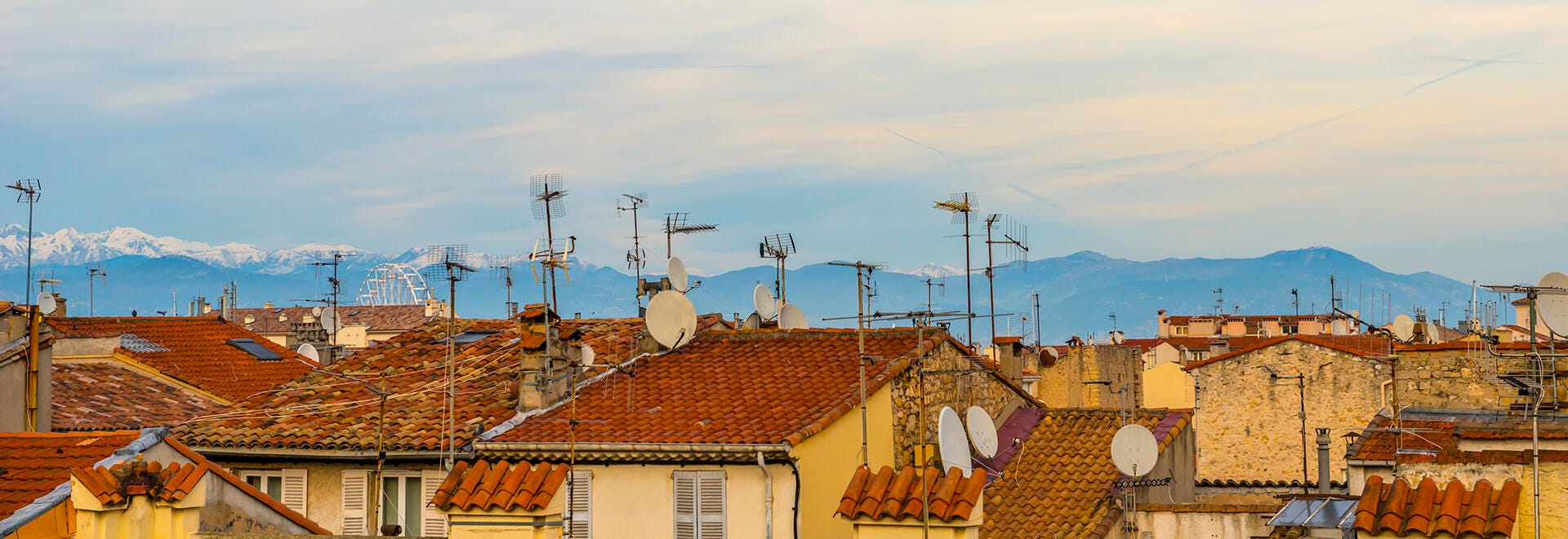 A rooftop with mountains in the distance and lots of antennas.