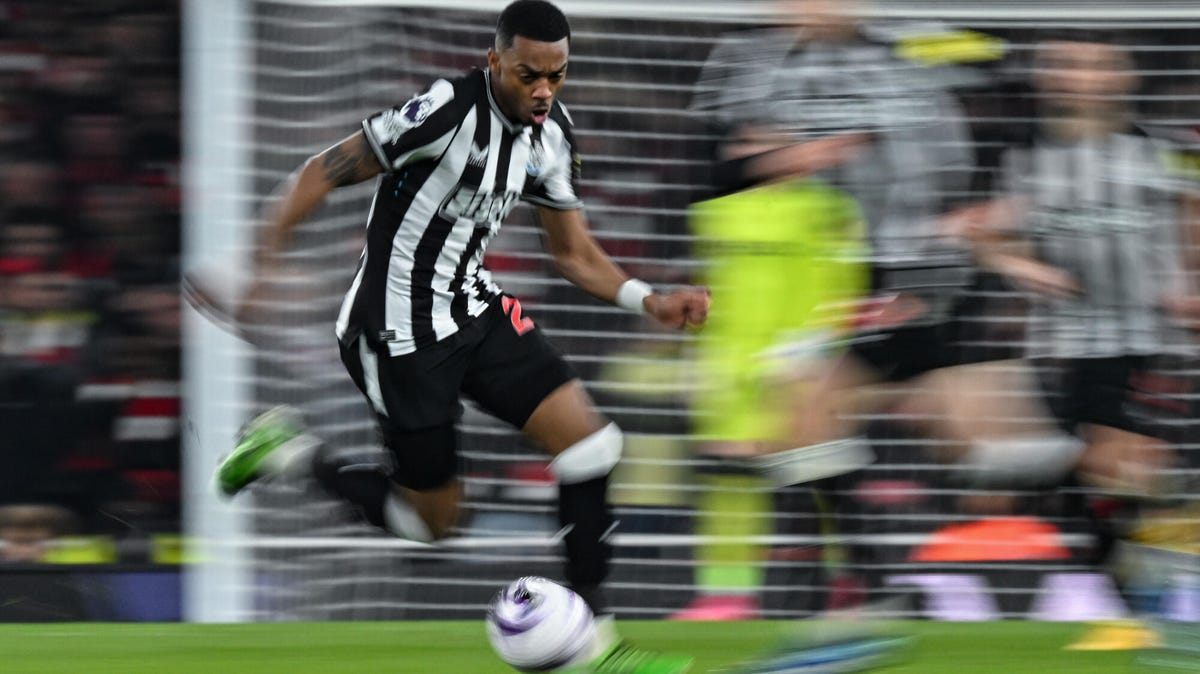Joe Willock of Newcastle United running with the ball with the background blurred.
