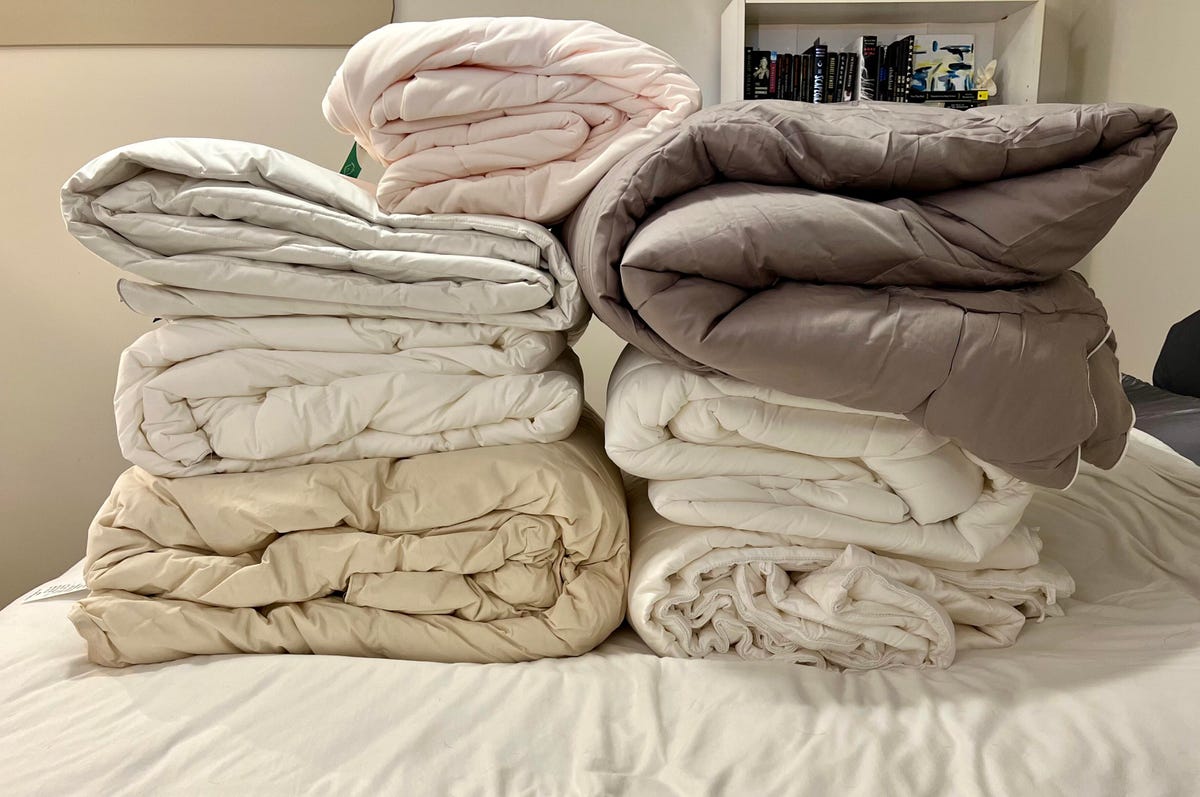 Seven comforters on a bed for testing.