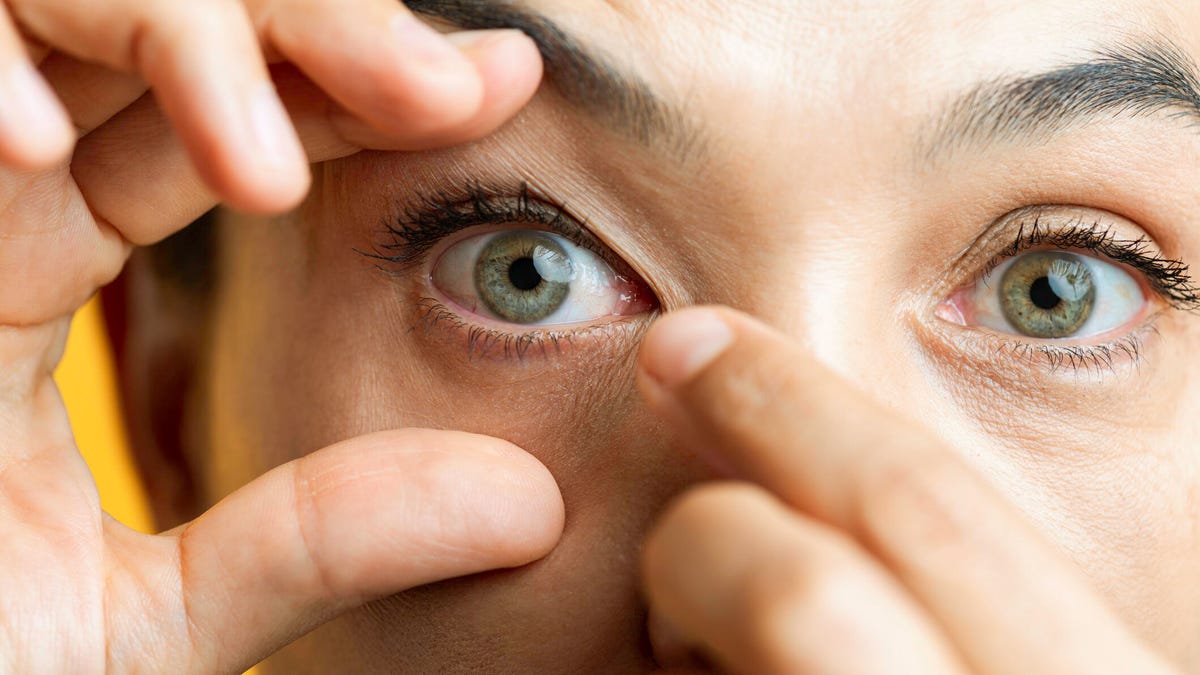 Woman holding open eye and trying to get something out of it
