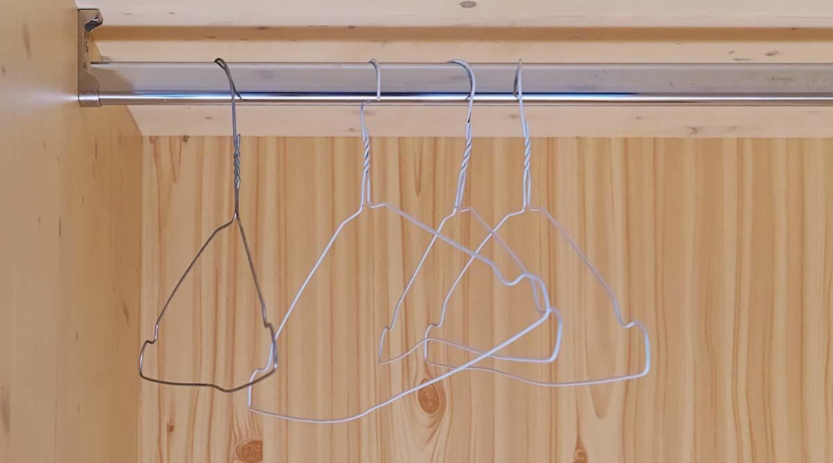Metallic handcrafted hangers hanging in wooden empty cabinet