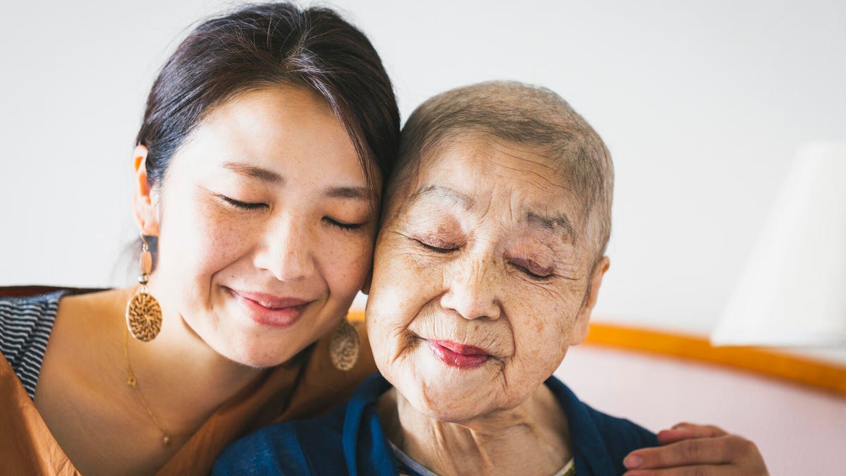 A younger woman embraces an older woman with thinning gray hair.